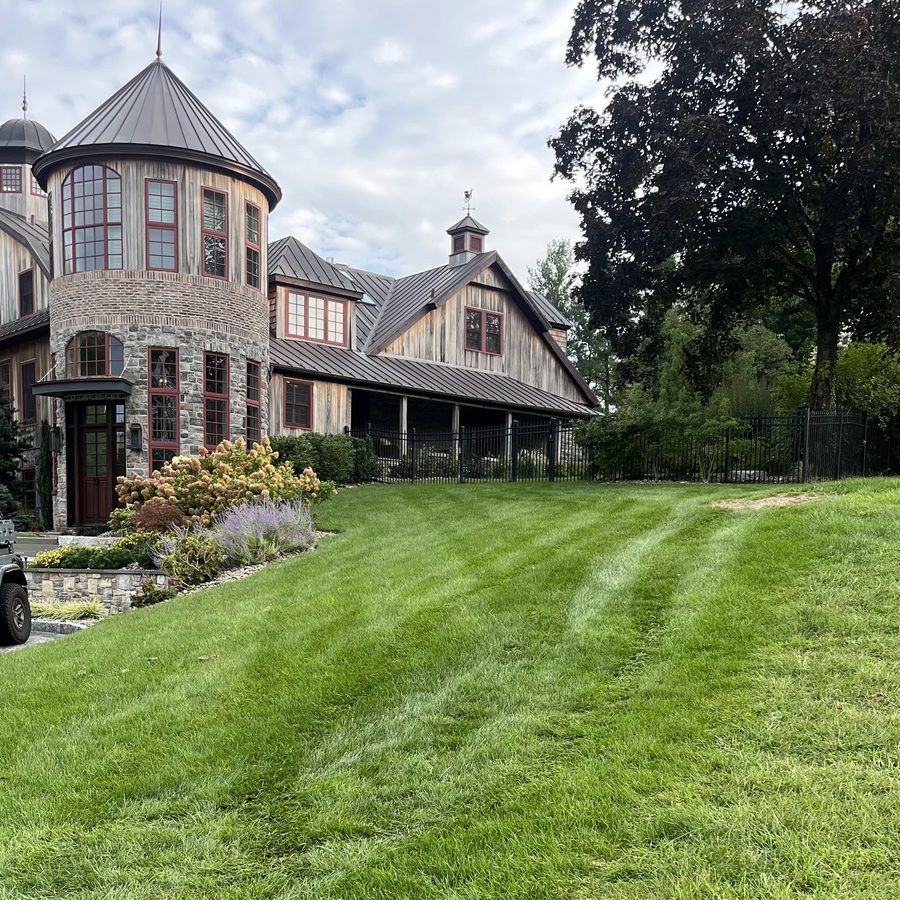 Striped lawn in front of a stone and timber home with a turret