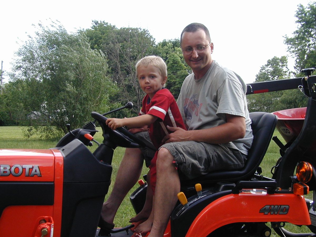 Jake as a young boy on the Kubota tractor with his dad